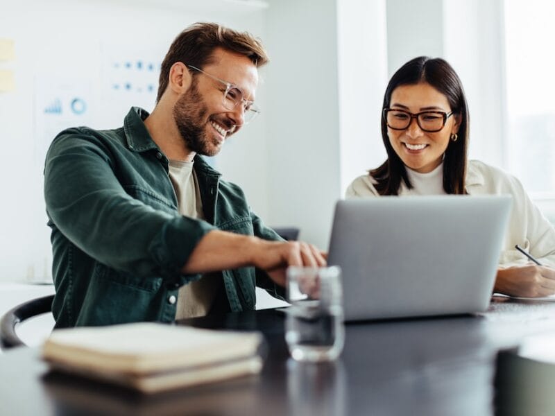 Two business people using a laptop together in an office.
